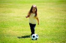 Girl kicking soccer ball on the grass